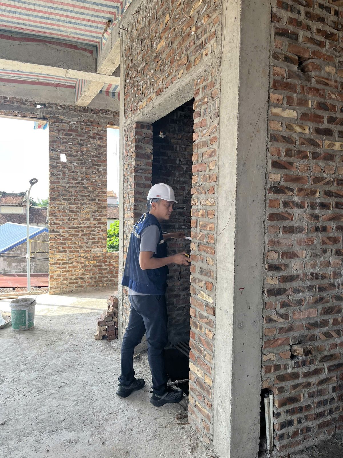 Kỹ sư mặc đồ bảo hộ đo kiểm giếng thang tại công trình